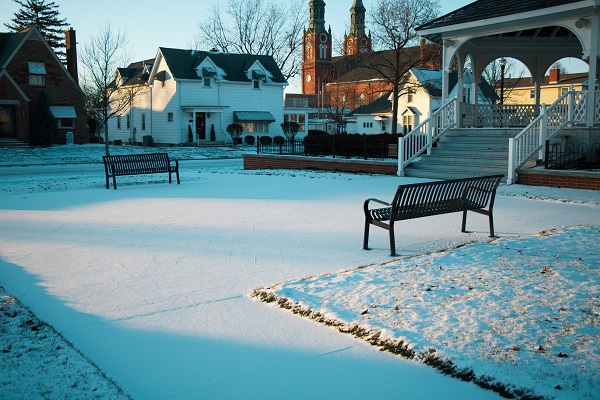 A park area with benches covered in snow